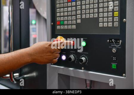 Machine operator hand turns on control panel of industrial machine. technician push button on control panel Stock Photo