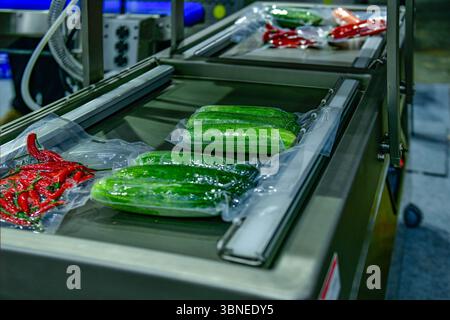 Fresh vegetables packed in a clear plastic wrap production line in factory, industrial food production Stock Photo