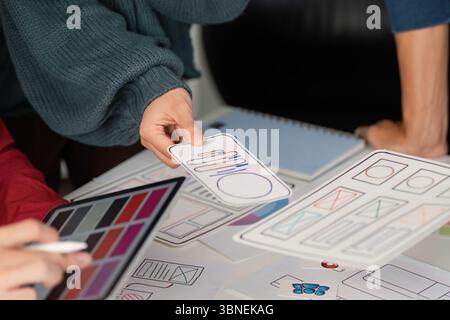 User Experience Design and Presentation. Designers showcasing mobile user interface layouts while discussing project ideas. Stock Photo