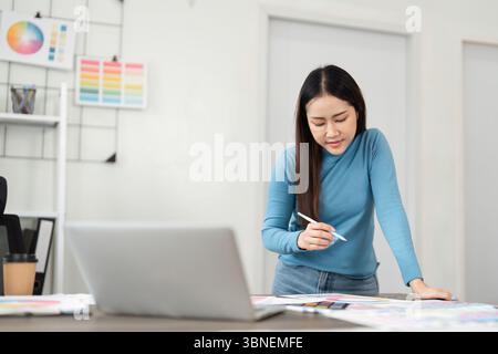 Design Workspace and Creative Planning. A designer focuses on color palette selection while analyzing digital resources. Stock Photo