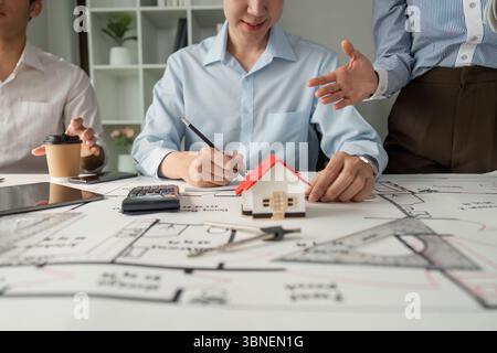 Team Collaboration and Architectural Planning. Professionals collaborating on building design, reviewing plans and models. Stock Photo