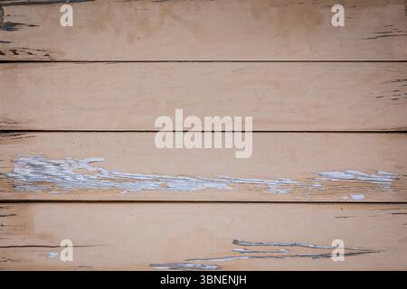Top-down view of an old beige wooden table surface with cracked and peeling paint, showing rustic texture and worn details. Stock Photo