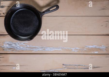 Small cast iron skillet with integrated iron handle in the upper left corner on a neutral background. The rest of the frame leaves empty space Stock Photo