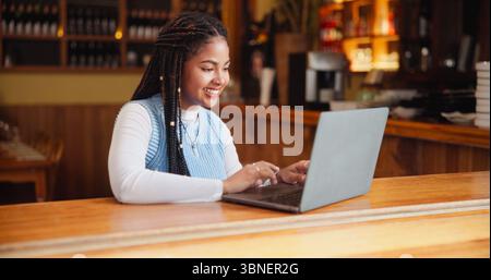Student, laptop and woman in cafe, smile and research for university project, internet and scholarship. Happy, pc and person in restaurant, connection Stock Photo