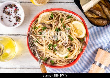 Sardinecore trend food, sardine pasta for dinner in plate on kitchen table. Spaghetti pasta with spices, herbs, lemon and canned sardines, copy space Stock Photo