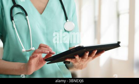Healthcare Professional Using a Tablet in a Bright Medical Setting Stock Photo