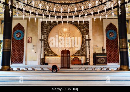 Inside a beautiful mosque. A Muslim man in traditional clothes prays during the holy month of Ramadan Stock Photo