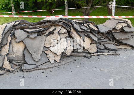 Pile of broken asphalt pieces with caution tape in outdoor area. Stock Photo