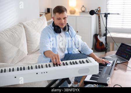 Man working with digital piano and MIDI keyboard in home studio Stock Photo