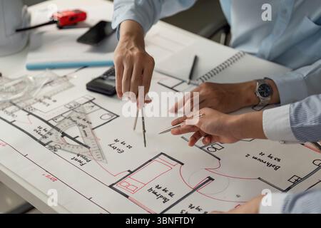 Collaboration and Architectural Design. Two professionals meticulously analyzing architectural blueprints using compasses and rulers. Stock Photo