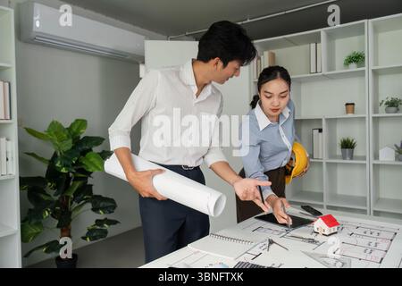 Project Discussion and Collaboration. Team members engaging over architectural plans and a model house. Stock Photo