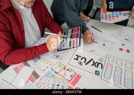 Creative Collaboration and Design Prototyping. Team members engaged in a lively session, refining design ideas using digital tools and paper Stock Photo