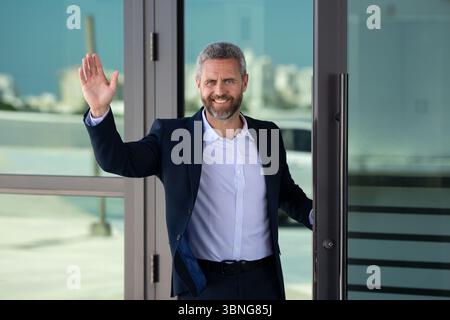 Businessman entering an office building. Mature businessman walking into a meeting. Businessman stepping through an office door. Charismatic Stock Photo