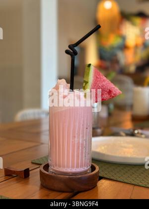 Banana strawberry smoothie in a clear wavy glass. Stock Photo