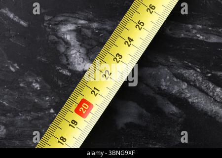 Yellow tape measure. Metric tool for measuring length on dark background. Construction and DIY concept. Accuracy in work. Stock Photo