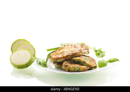 breakfast of zucchini pancakes with green onions in a plate on a white background. Stock Photo