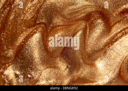 Glowing golden shimmering cosmetic texture of gel or body spray. Background texture for backdrops or mapping. Stock Photo