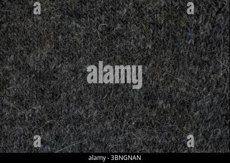 Close view of dark gray knitted fabric reveals intricate texture and fine fibers, highlighting textile craftsmanship. Stock Photo