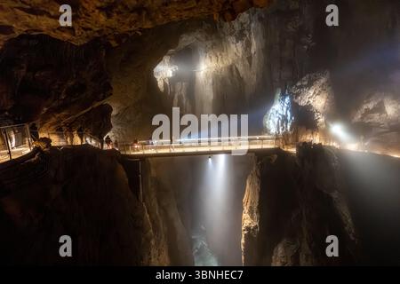 Tourists exploring a large cave, walking on a bridge over a chasm, Skocjan cave, Slovenia Stock Photo