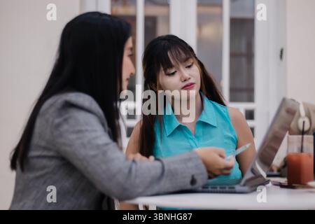 Two young professionals are collaborating on a business project, reviewing financial data, strategizing solutions and having a meaningful discussion u Stock Photo
