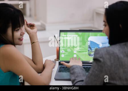 Two businesswomen collaborating. They review a business proposal presented on a laptop. Sharing ideas and talking about new project strategy Stock Photo