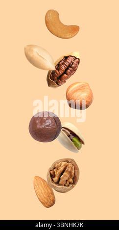 Peanut and other nuts falling on beige background Stock Photo