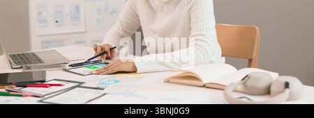 Asian adult woman's hands are designing mobile app interface on tablet for good user experience. Focus on website wireframe creation in design process Stock Photo