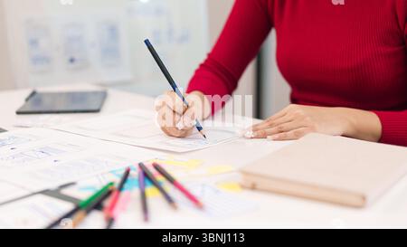 Close-up shot of an Asian adult woman hands drawing a wireframe on paper. Crafting user interface for a mobile application with design and creative pr Stock Photo