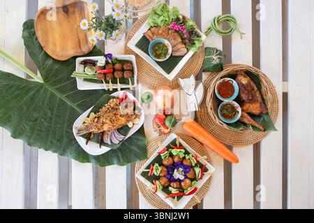 A beautifully arranged traditional Thai food set placed on a wooden table with natural light. The image features a variety of authentic Thai dishes in Stock Photo