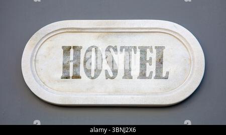 HOSTEL text marble sign on grey blue wall Stock Photo