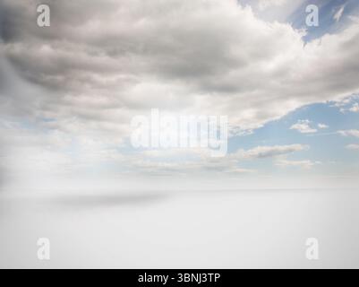 Abstract flat design horizon showing white plane meeting horizon under clouds and pale blue sky Stock Photo