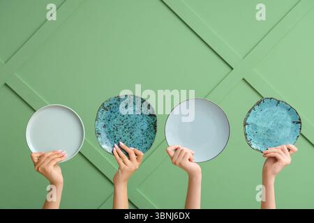 Hands holding empty plates on green background Stock Photo