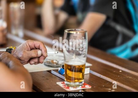 A group of friends are sitting in a pub, smoking cigarettes and drinking beer. Stock Photo