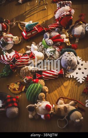 A high-angle view of a collection of various Christmas ornaments scattered on a wooden table. Knitted penguin and Santa, glass baubles, felt snowflake Stock Photo