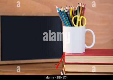 Desk organizer on stack of books against blackboard Stock Photo