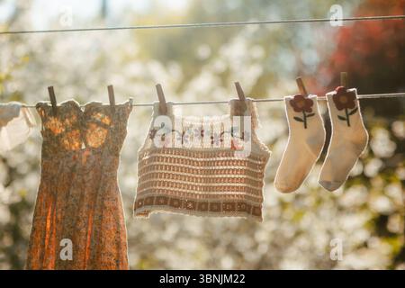 A vibrant scene of freshly washed clothes hanging on a clothesline, basking in warm sunlight. The image captures the essence of simple, sustainable li Stock Photo