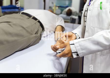 A medical professional checks a patient's oxygen saturation and heart rate using a pulse oximeter in a clinical setting, showcasing essential healthca Stock Photo