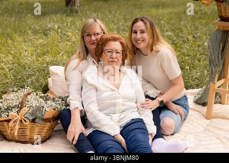A heartwarming image featuring three generations of women, grandmother, mother, and daughter enjoying a serene day outdoors, epitomizing family ties a Stock Photo