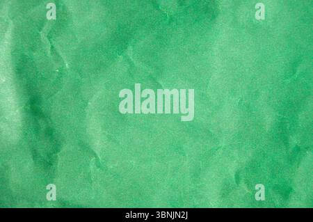 Green paper background. Wrinkled green wrap paper close-up. Crumpled packaging paper texture. Creased green paper blank texture. Stock Photo