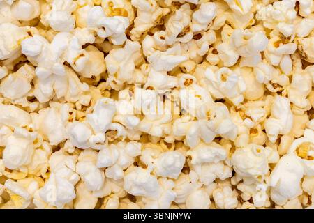 Detailed close-up image of fluffy, white popcorn kernels. Ideal as a background featuring the texture of this popular, light snack. Perfect for food-r Stock Photo