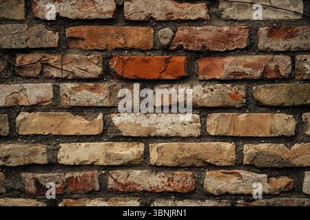 Close up of a rustic brick wall showcasing earthy tones and natural textures. The aged surface features varying shades of brown and red, providing a w Stock Photo