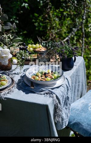 A vibrant salad featuring lamb's lettuce, grapes, cashews, and walnuts, beautifully arranged on a table outdoors. The sunlight enhances the freshness Stock Photo