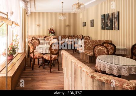 A charming retro cafe interior featuring vintage furniture, floral patterns, and soft lighting. The ambiance is cozy, evoking nostalgia and classic el Stock Photo