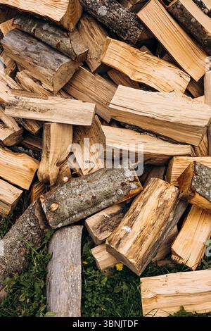 A collection of chopped logs stacked on the ground, showcasing natural wood textures and variety in shape and size. Rustic scene perfect for themes of Stock Photo