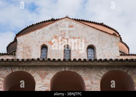 A historic brick facade adorned with arched windows and a cross in Murano, Venice. The architectural details reflect the rich cultural heritage of the Stock Photo