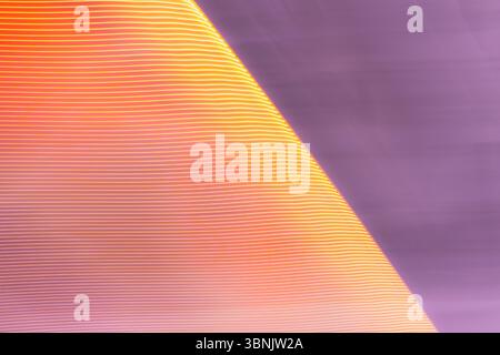 An abstract light background featuring soft, flowing lines in shades of purple and orange. The wave like pattern and gradient create a dynamic, soothi Stock Photo