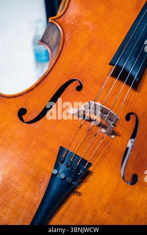 A detailed close-up photograph of a cello emphasizes the instrument's strings and beautifully crafted wooden body, showcasing the fine artistry and te Stock Photo
