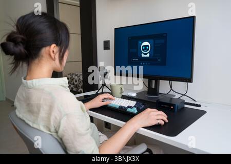 A young professional working in a minimalist home office uses a robot assistant to boost productivity. The digital interface and mechanical keyboard e Stock Photo