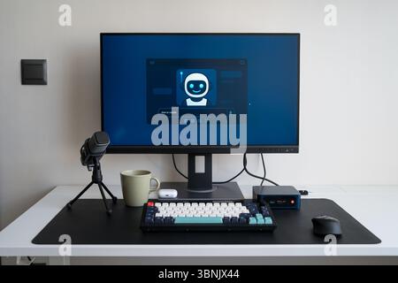 Modern home office setup featuring a computer screen displaying an AI assistant interface, a keyboard, microphone, and coffee cup, creating a tech-sav Stock Photo