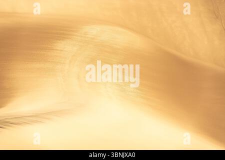 Captivating image of golden sand dunes showcasing intricate textures under warm sunlight. The flowing patterns create a serene and mesmerizing natural Stock Photo